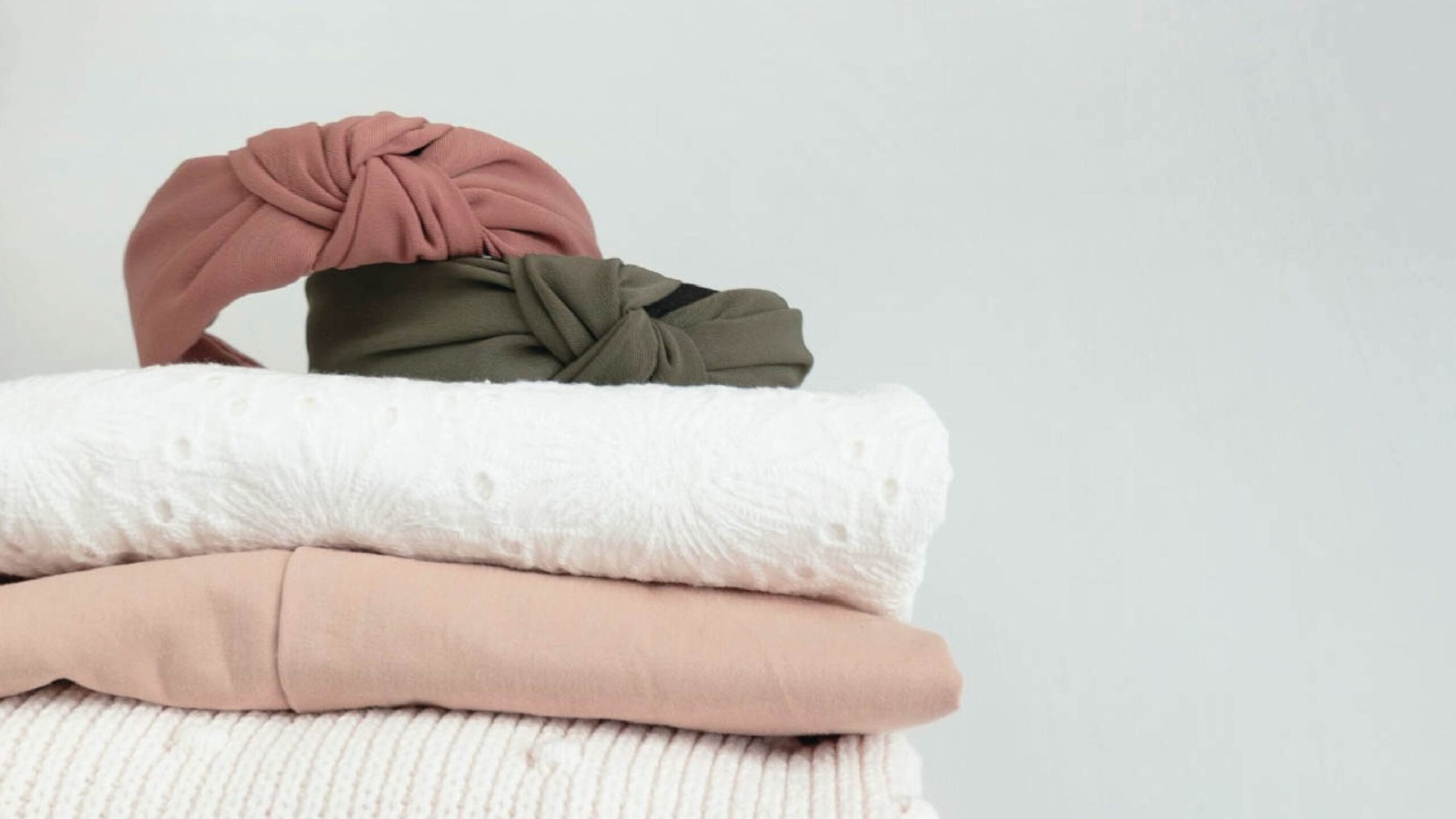 Maglioni, camicie e fasce per capelli piegati e impilati con cura, pronti per il cambio armadio.